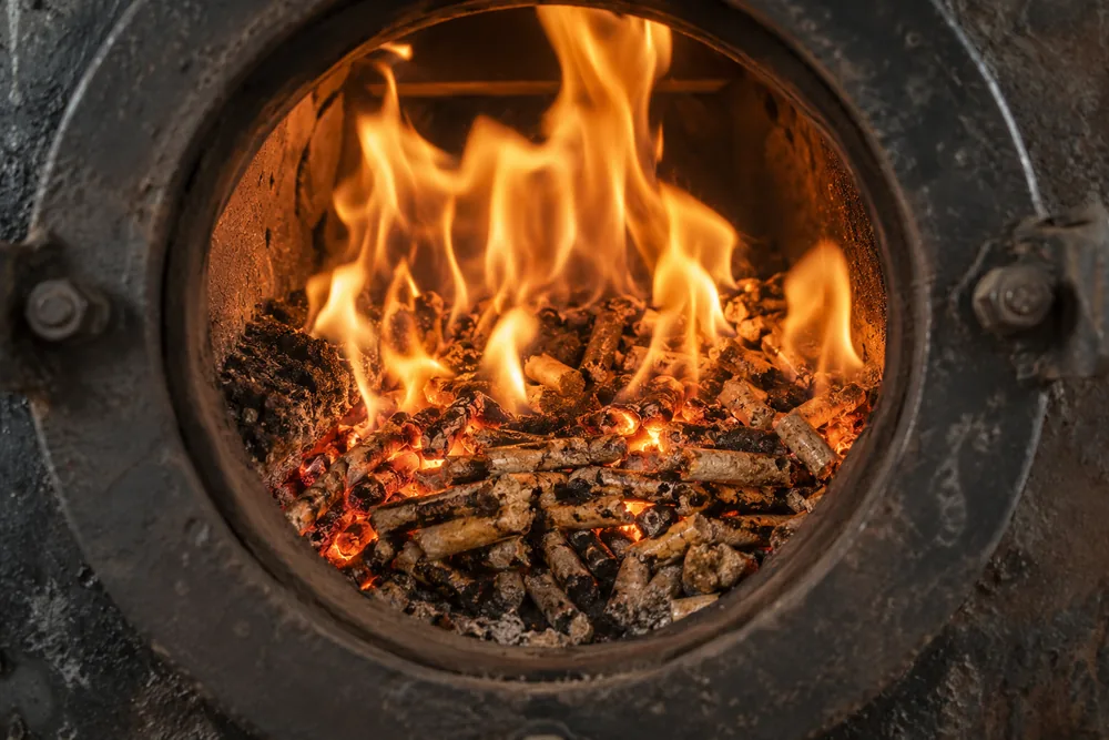 Clean orange flame bed of burning pellets seen through a boiler port