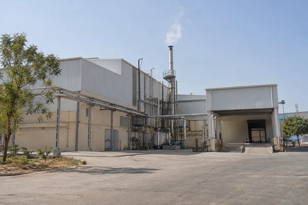 Indian food processing factory with white steam rising from its boiler chimney