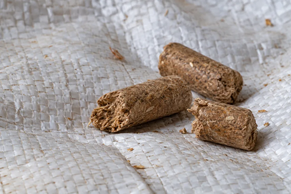 Biomass pellets resting on a white woven polypropylene sack